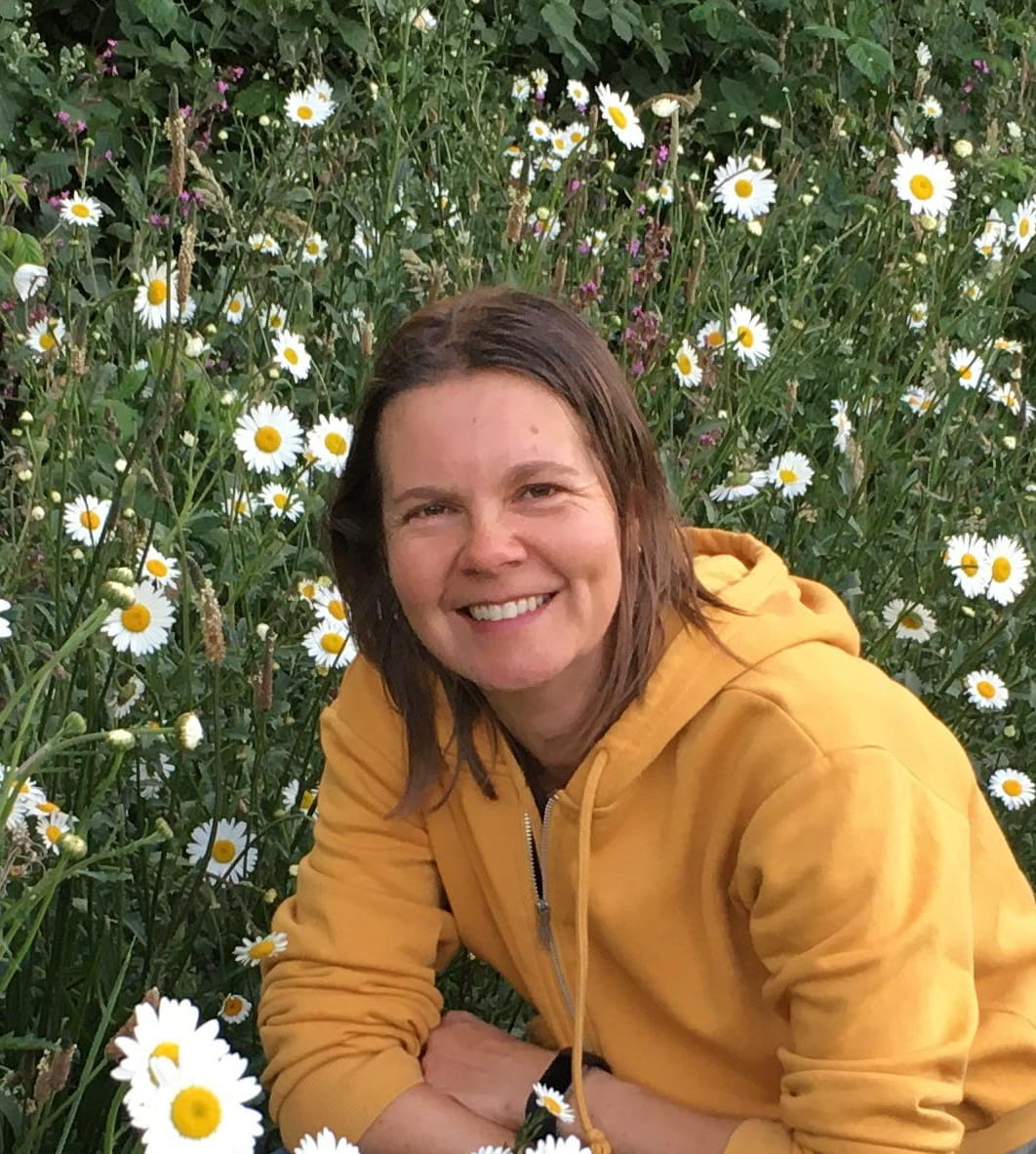 Esther lachend in een bloemenveld met margrieten